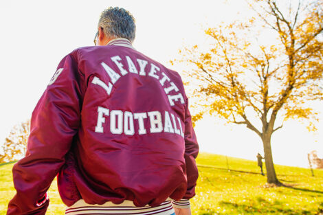 person wears Lafayette Football jacket, sun shines, green grass