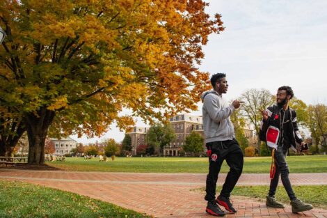 two students walk and smile on a brick pathway on the Quad