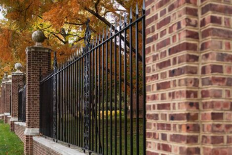 fall foliage near a brick and iron fence