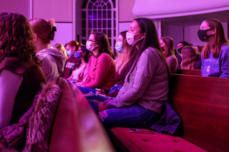 A crowd of masked students watch hypnotist Erick Kand.