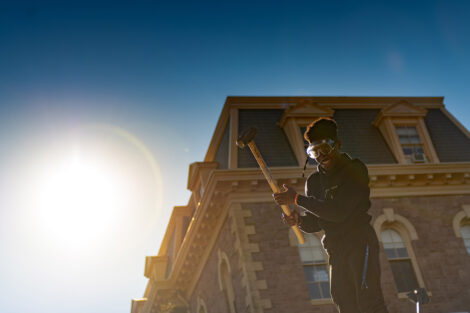 A student hits an SUV with a sledgehammer in front of Pardee Hall.