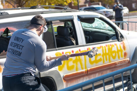 A student hits an SUV with a sledgehammer. The vehicle has 