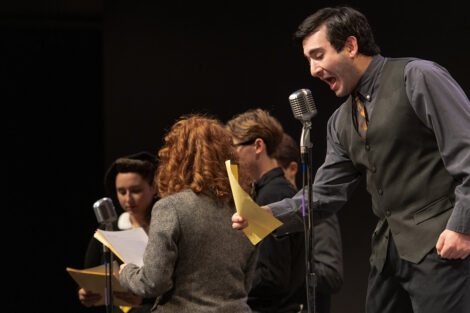 student performers in vintage clothing perform on stage with retro microphones