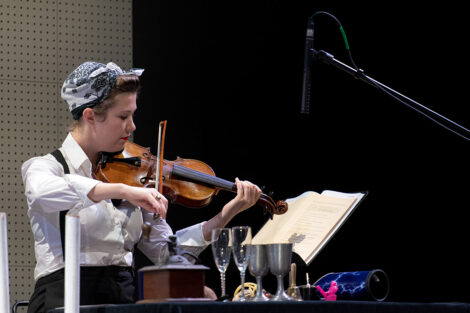 student performer plays violin on stage
