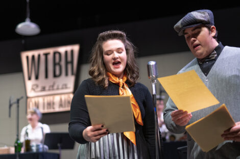 student performers in vintage dress gather on stage with vintage microphones