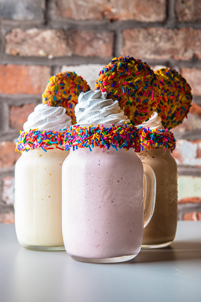 Milkshakes, topped with sprinkles and cookies.