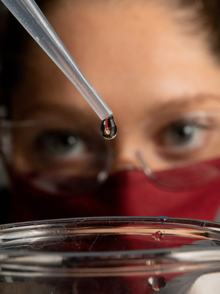 Natalie_Kucowski holds a dropper to a beaker.
