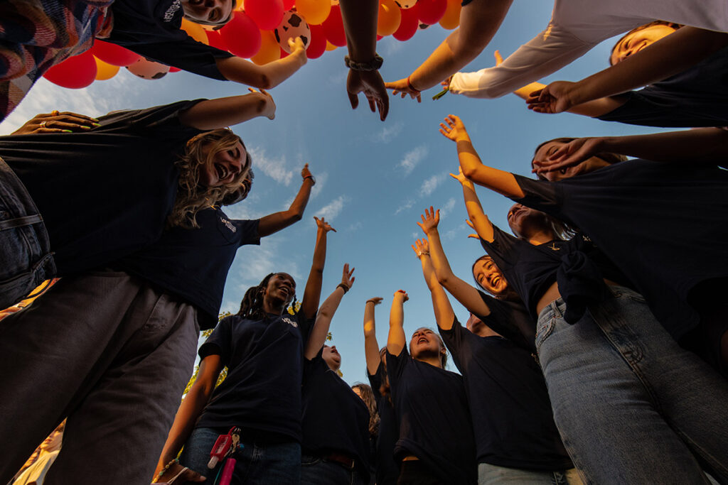 Students raise their arms in a circle.