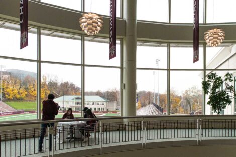 videographer captures two students and coach Ryan Adams painting a sign in Kirby Sports Center
