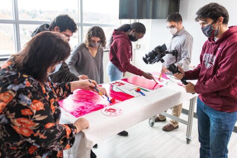 Lisa Karam and engineering students paint a sign in Acopian