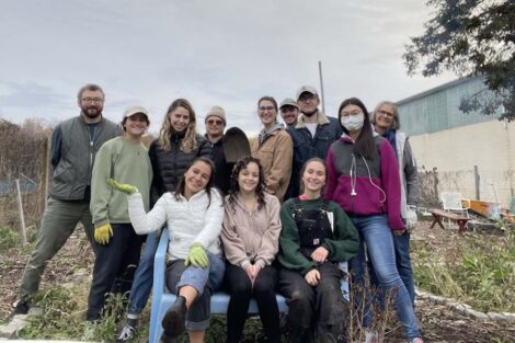 A group of students pose on a bench together at the Easton Urban Farm