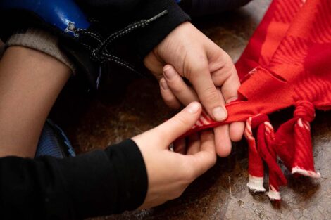 Young hands knot a blanket together