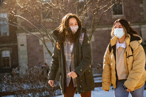 Two students, masked, walk outside.