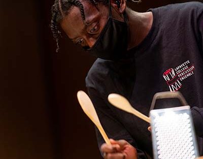 student uses wooden spoons as drum sticks