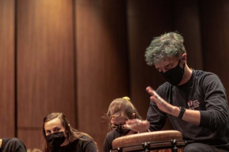 drummer with green tinted hair looks wild eyed as he hits the drum