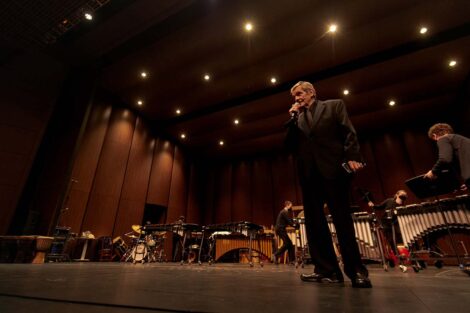 Prof. Stockton speaks to the audience as students move instruments