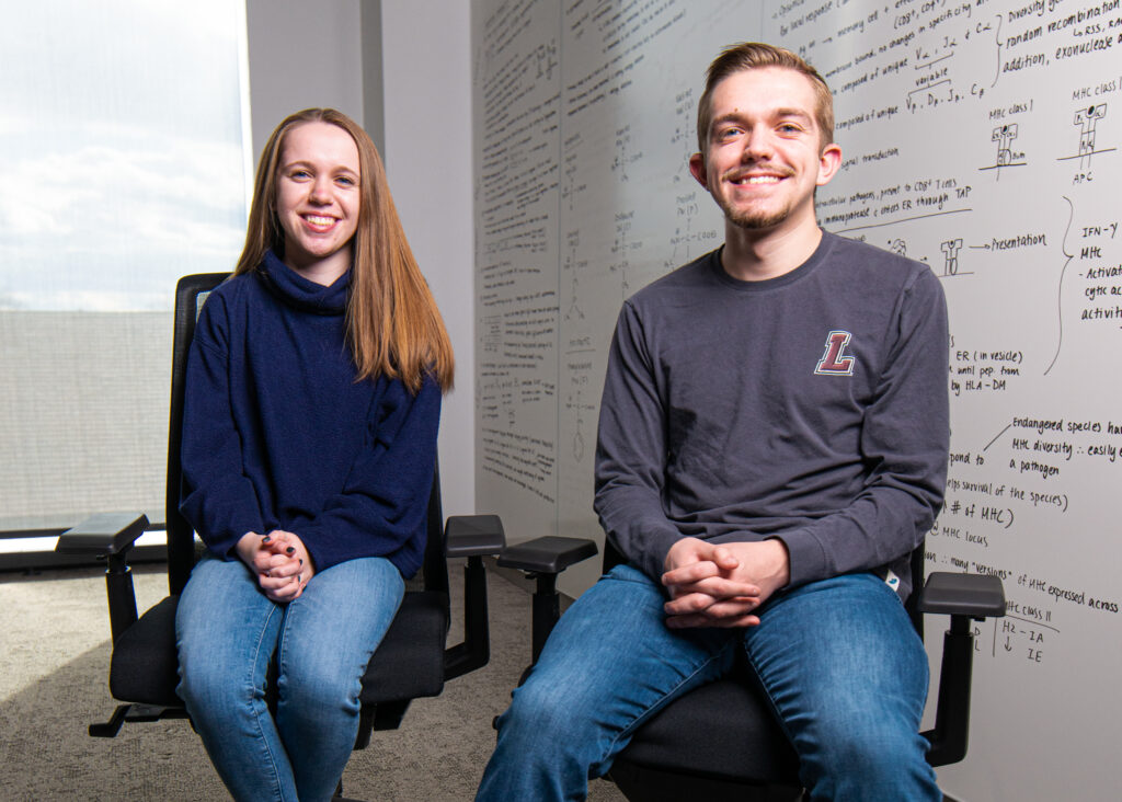 Twin Lafayette students Abbey and Sam Milhaven sitting next to each other in a classroom in front of a white board