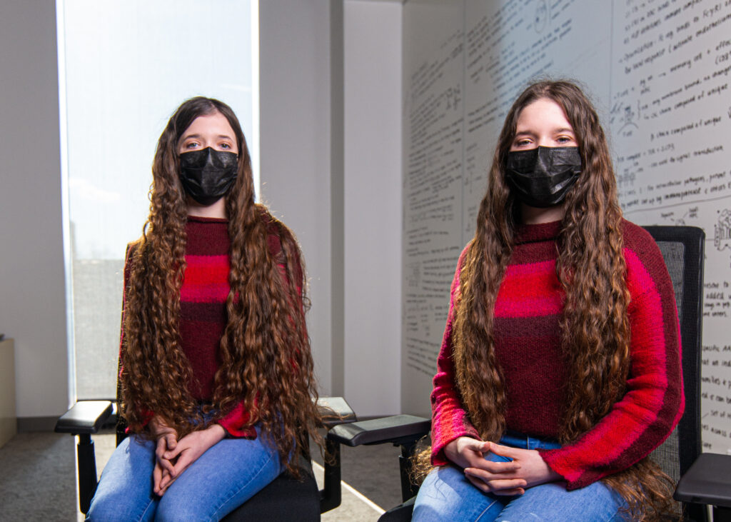 Identical twin Lafayette students Elonne and Qwin Pisacane sitting next to each other in a classroom in front of a white board
