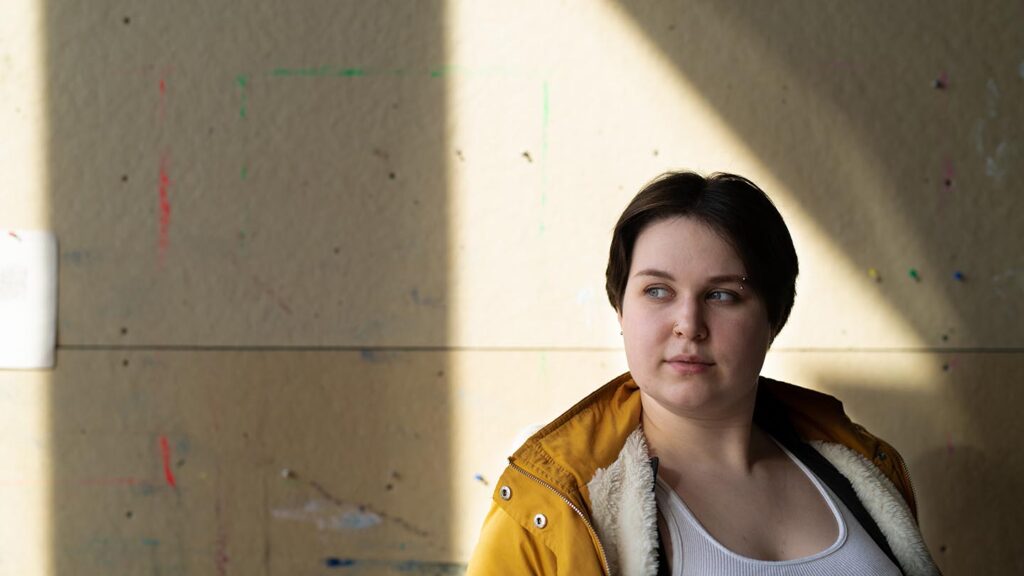Student in a triangle of light looks out of the corner of her eye