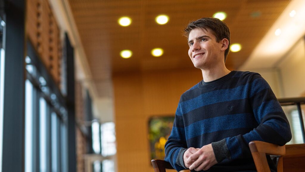 Student sits in chair in Skillman Library and smiles