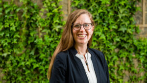 Erin Cottle Hunt smiles, ivy on a stone building behind her