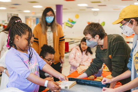 Lafayette student guides young elementary students through a paper making activity