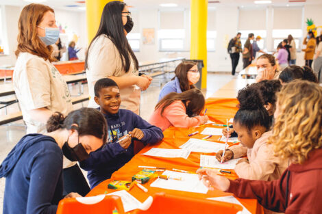 elementary school students sit at a table and color