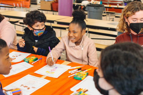 elementary school students sit at a table and color
