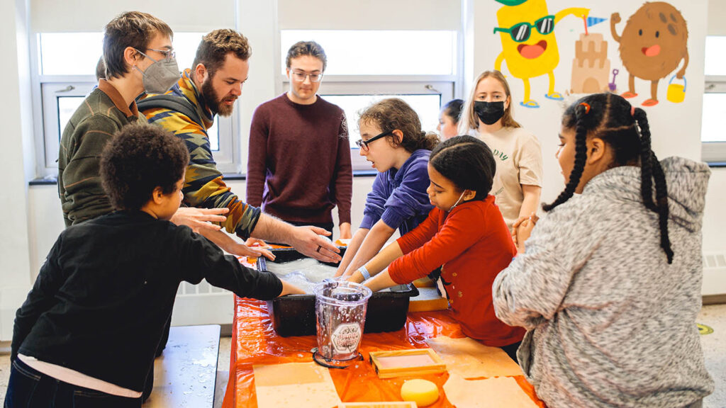 Lafayette student guides young elementary students through a paper making activity