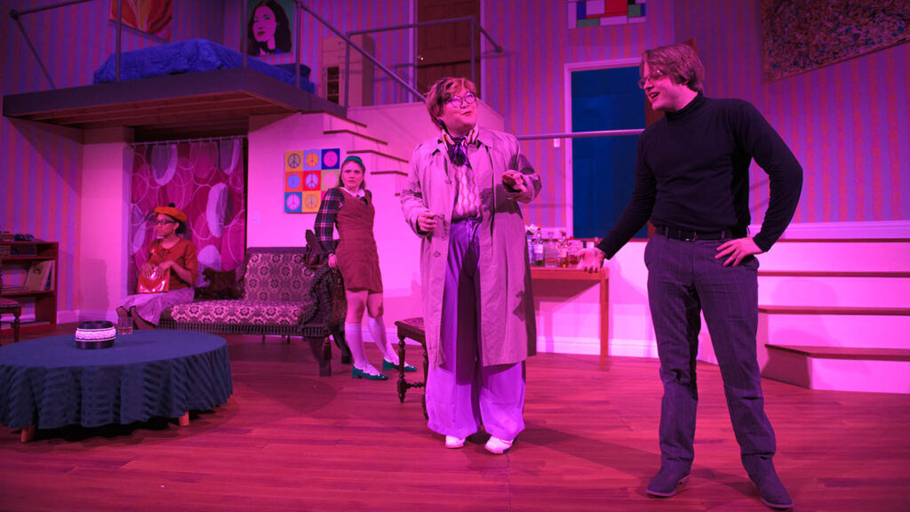 students in a stage production act on stage with pink dramatic lighting