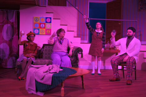 students in a stage production act on stage with pink dramatic lighting