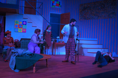 students in a stage production act on stage with blue dramatic lighting