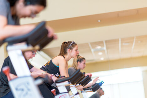 a group of students are lined up on spin bikes