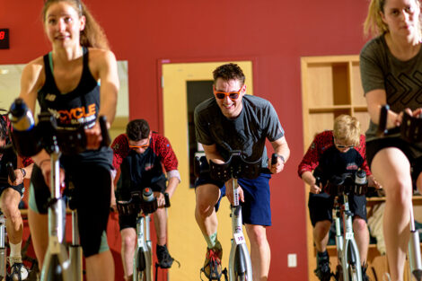 students ride spin bikes
