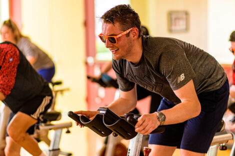 students ride spin bikes