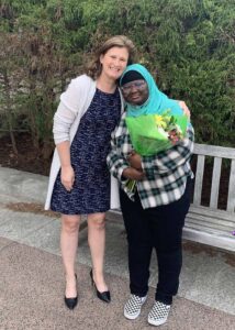 President Nicole Farmer Hurd stands with her arm around Fatimata Cham, who holds flowers