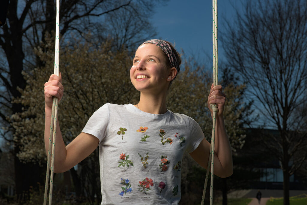 Kristen Steudel smiles as she looks to the right, sitting on a swing.