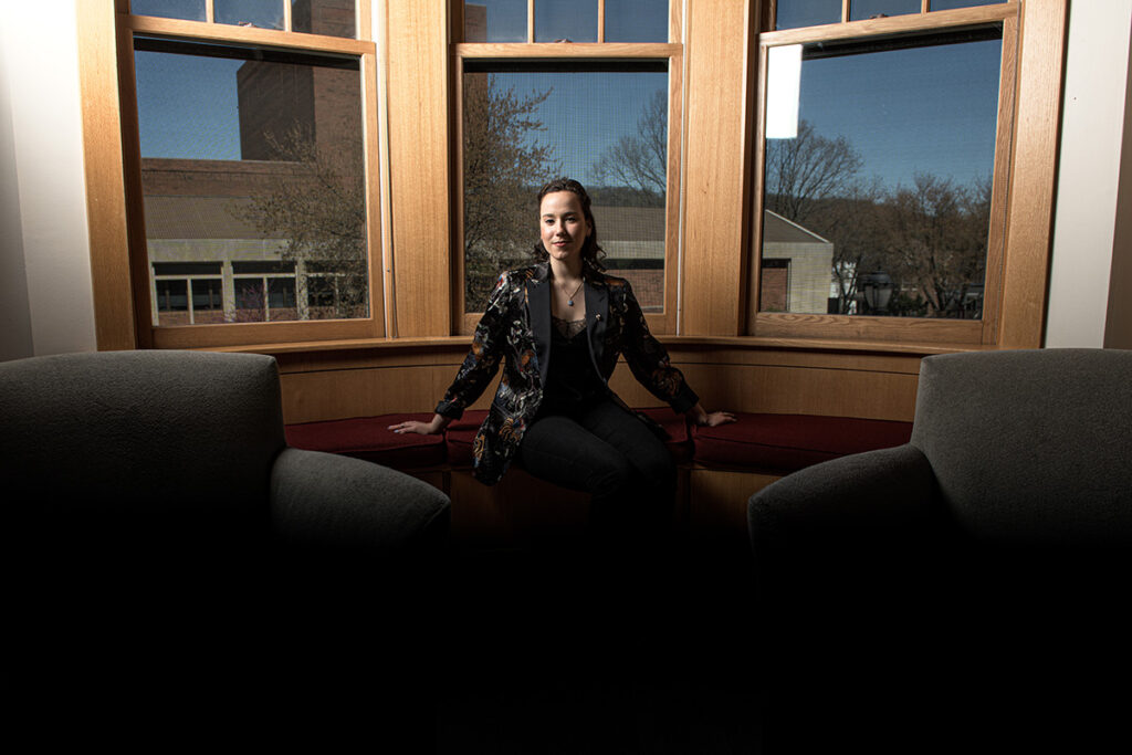 Milena Berestko smiles in front of large windows.