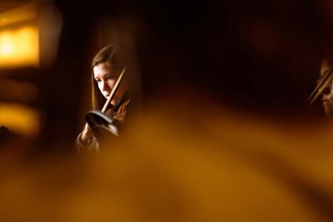 Anna plays violin with yellow light around her