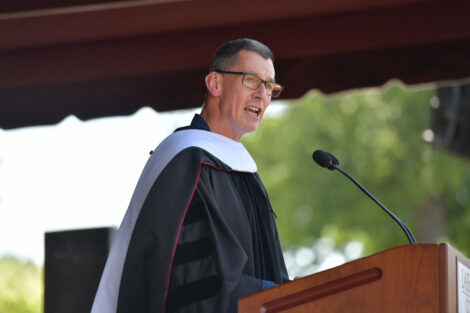 Chip Bergh in regalia stands at podium at Commencement