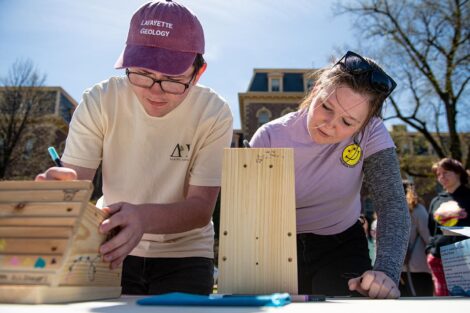 two students use markers to decorate blocks of wood