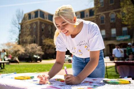 student smiles while coloring at a table with Pardee in background