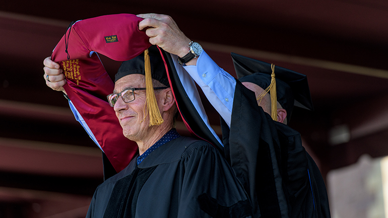 trustee places hood around Chip Bergh's neck