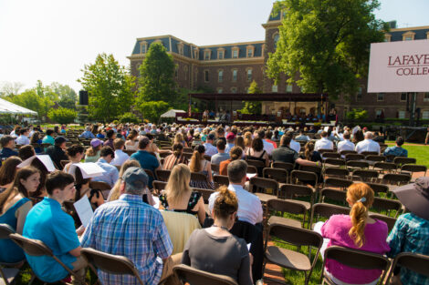 family members sit in seats in rows on Quad, Pardee in background