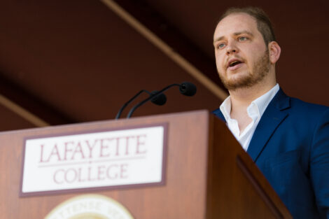 student in suit stands and talks at podium