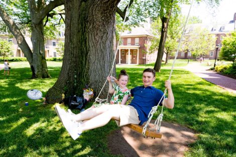 two young children swing on a swing on campus