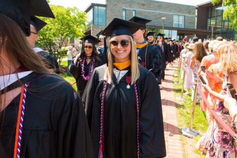 graduate in cap and gown and sunglasses smiles