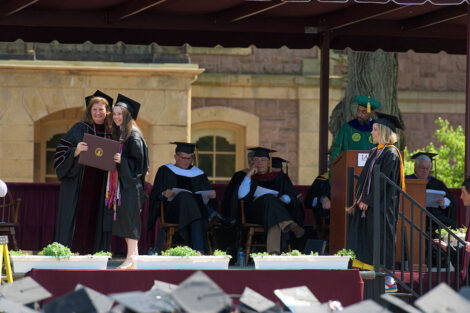 President Hurd smiles with graduate on stage as she hands student diploma