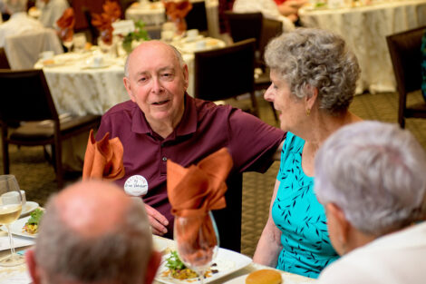 Two people talk while sitting at a table.