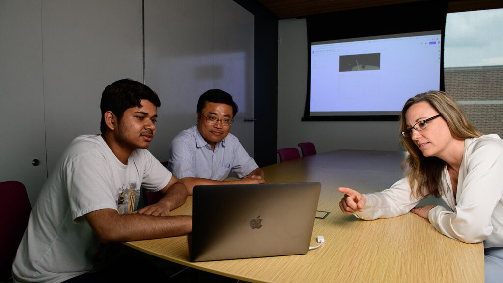 Prof. Yih-Choung Yu, Prof. Lisa Gabel, and Padmanabh Kaushik '25 sit together at a table and work on a laptop